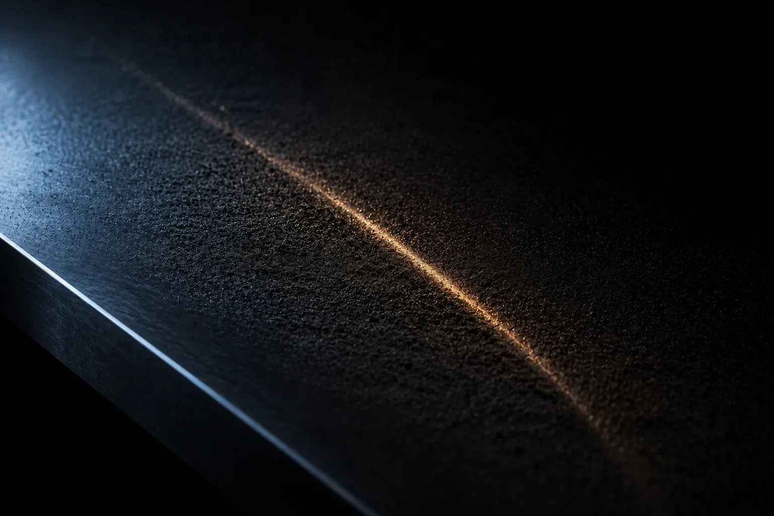 A thin layer of fine dark dust settled on polished steel, one single track through it