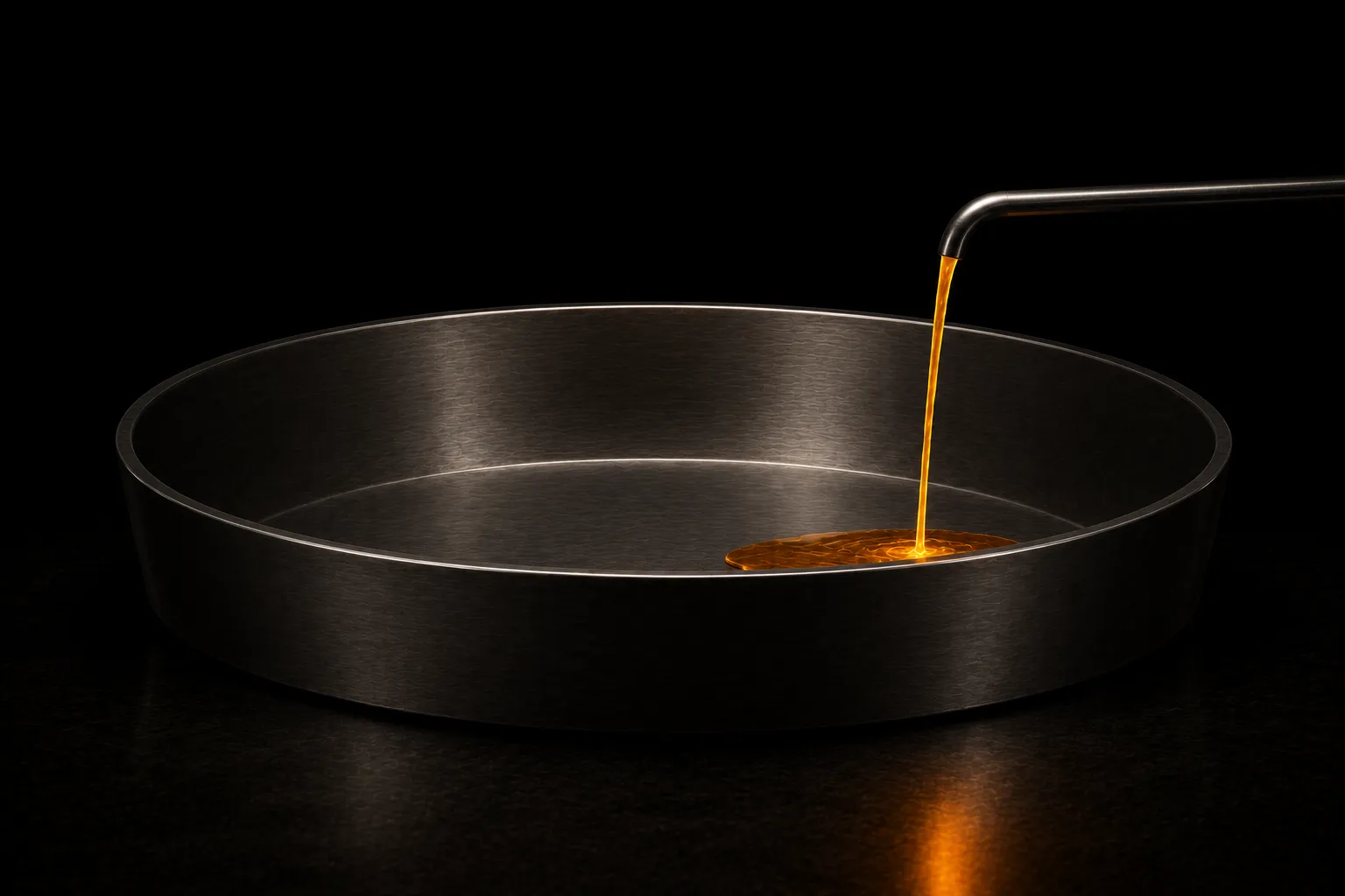A wide empty steel basin fed by one narrow pipe delivering a thin stream of glowing liquid, barely beginning to pool.