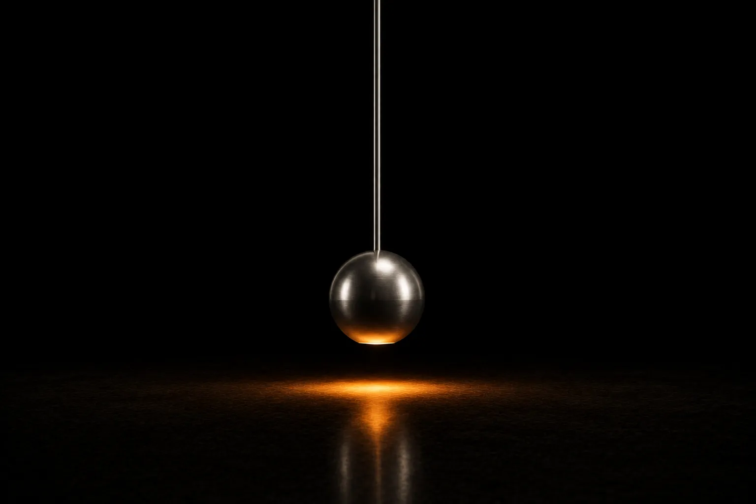 A polished steel pendulum hanging perfectly still and vertical above a low pool of warm light on a dark floor.