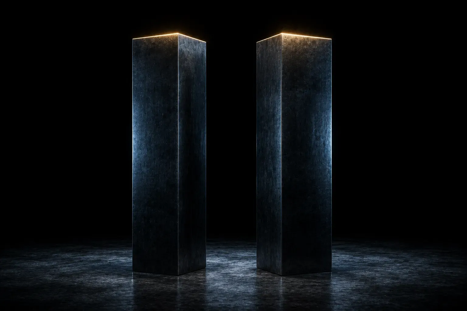 Two dark steel columns standing side by side, their top faces lit warm above everything around them